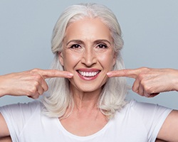 Senior woman pointing to natural looking denture