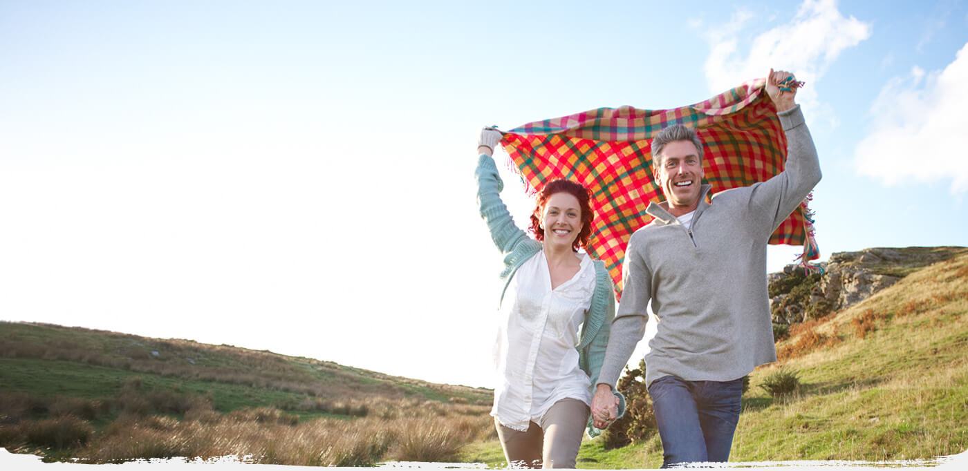 Smiling man and woman holding hands outdoors