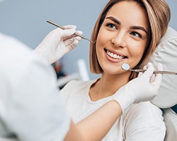 A young woman smiles while her dental hygienist prepares to examine her oral cavity