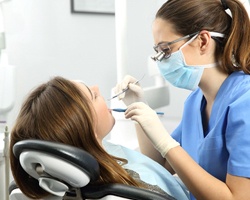 A young woman having her teeth cleaned by a dental hygienist