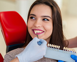 Woman's smile compared with tooth color chart