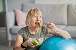 woman smiling while eating salad