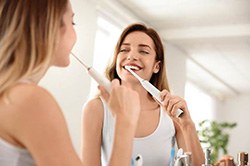 Woman brushing teeth to prevent dental emergencies in Weyauwega