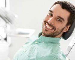 A young man lying back in a dentist’s chair and smiling after undergoing safe mercury removal