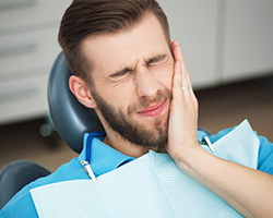 Man in dental chair holding jaw