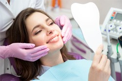 woman smiling while looking in dental mirror 
