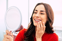 A young woman wearing a red blouse and smiling after receiving veneers