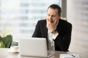 a man sitting at his computer yawning