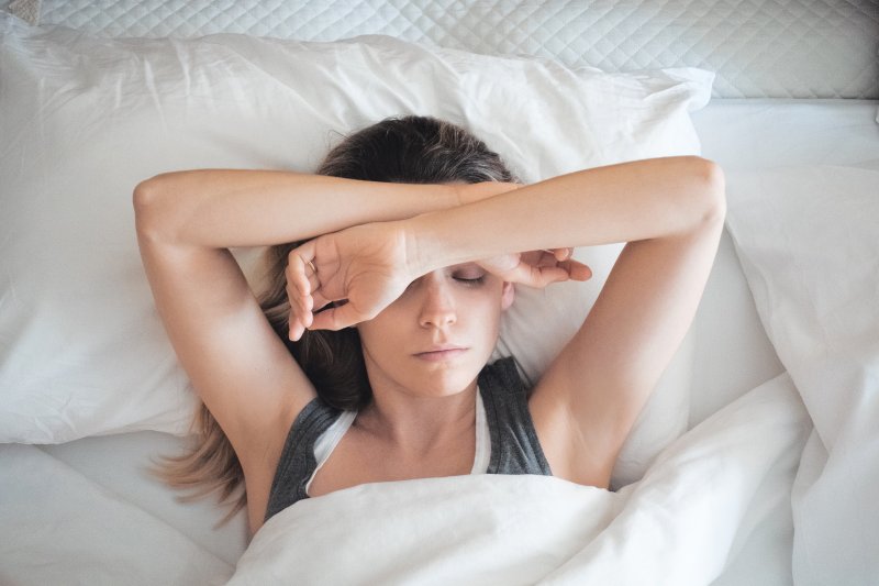 a tired woman lying in bed attempting to sleep