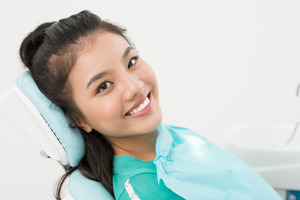 Female patient sitting back in dental chair and smiling